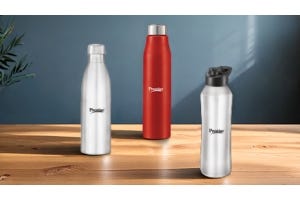 Four Prestige stainless steel water bottles in black, silver, and red colors displayed on green podiums against a tropical-themed green background.